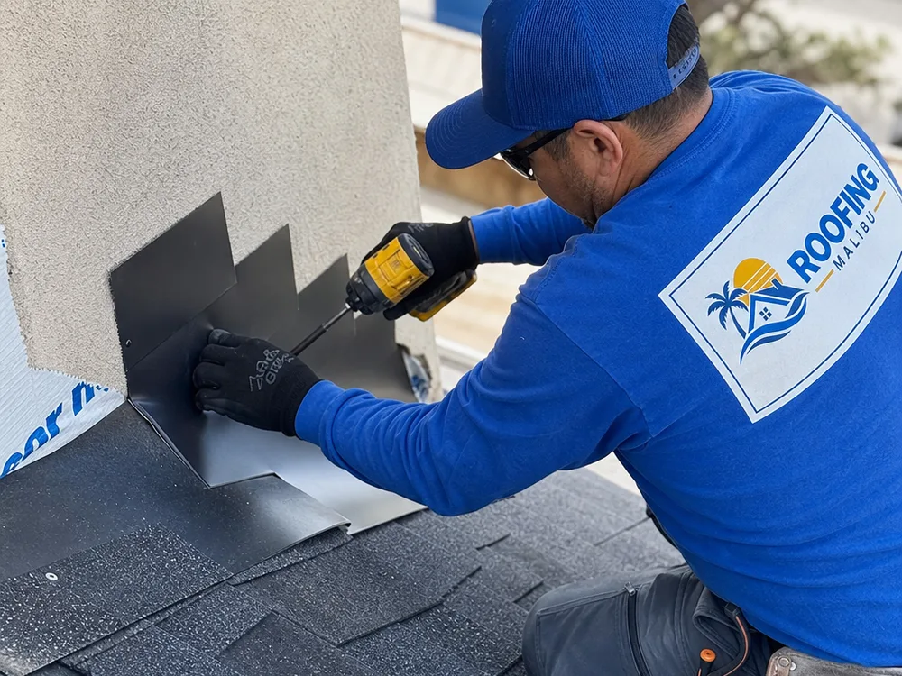 Roofer installing step flashing at a roof-to-wall intersection